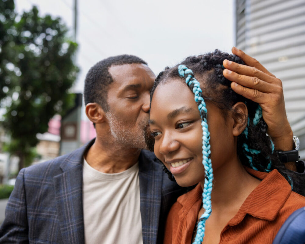Father kisses smiling daughter's head