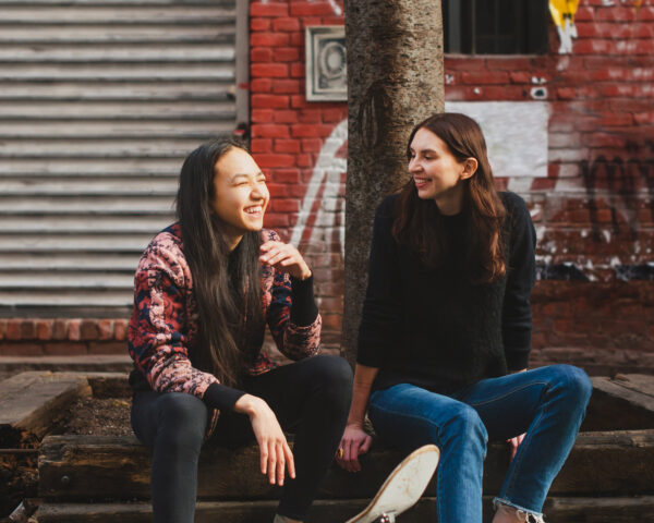 Adult and teen sitting outside laughing and smiling