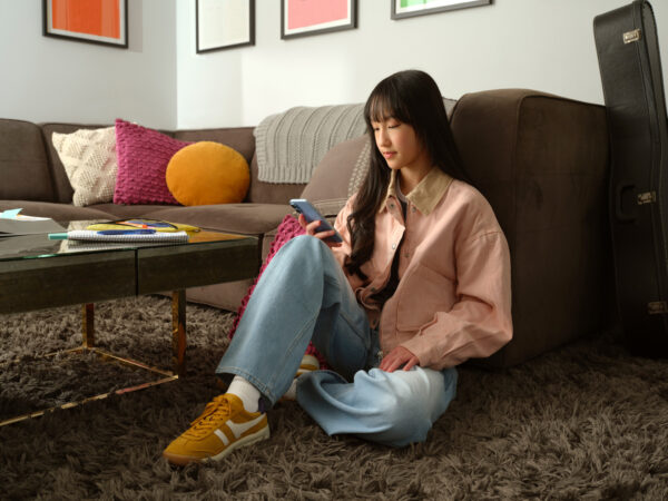 Teen girl sitting on carpet, texting