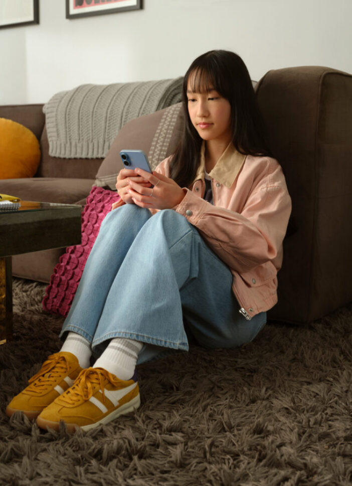 Teen girl sitting on carpet, texting