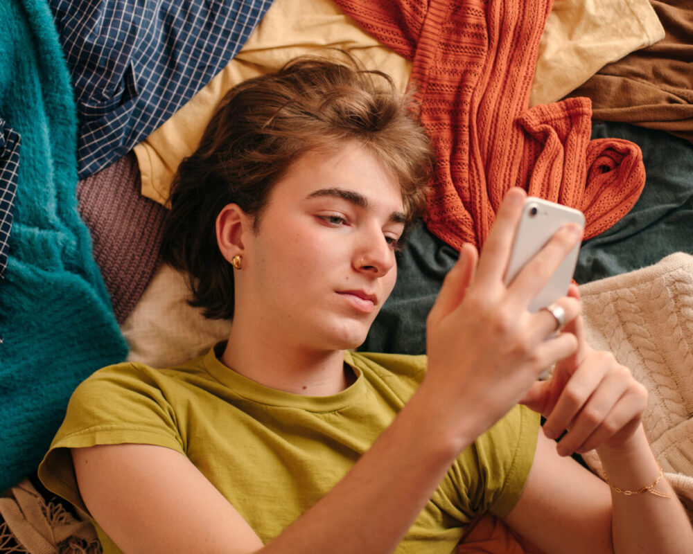Teen lying down looking at a phone